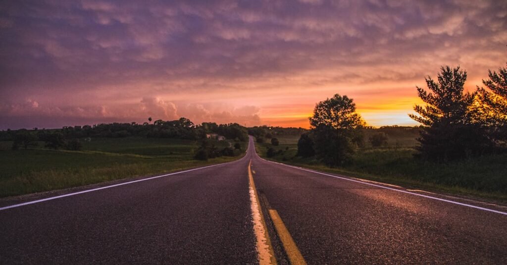 Picturesque view of an empty road stretching through rural Minnesota at sunset, framed by lush greenery.